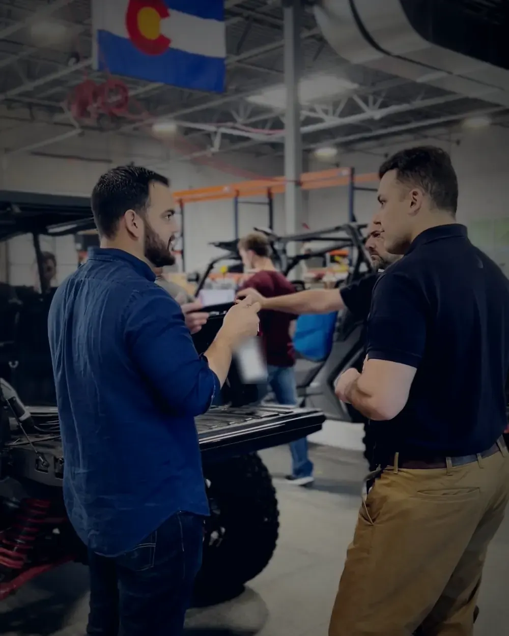 Cristian Liani talking with a customer beside utility vehicles in a workshop