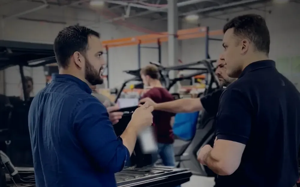 Cristian Liani talking with a customer beside utility vehicles in a workshop